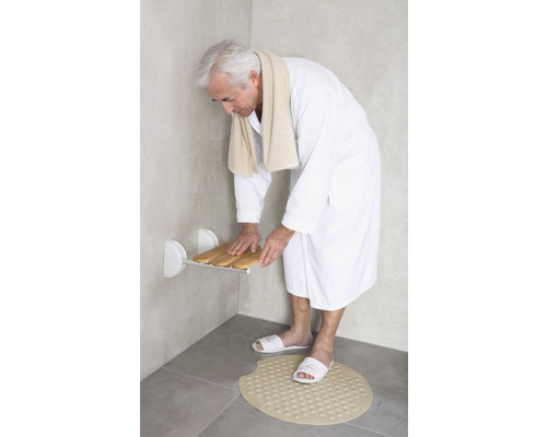 Homme dans une salle de bain avec siège de douche et tapis de bain