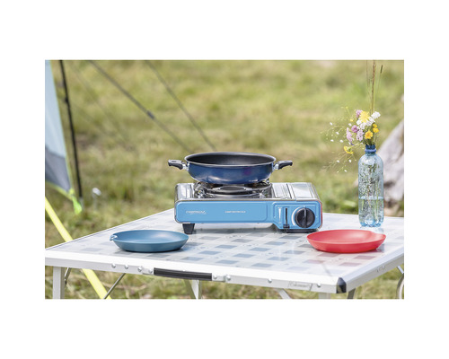 Campingszene mit Kocher, Pfanne und Geschirr auf einem Campingtisch