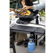 Scène avec un barbecue de table fixé à une table, utilisé par des personnes pour faire des grillades.