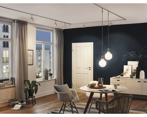 Séjour avec système de rails, spots, suspensions, table, chaises et commode.