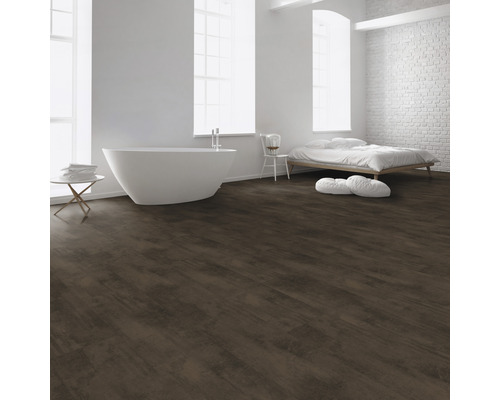Pièce claire avec baignoire, lit et revêtement de sol brun foncé imitation bois