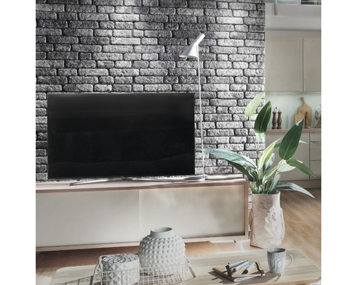 Salon avec mur d''accent en maçonnerie, télévision, lampadaire et éléments décoratifs sur une table basse