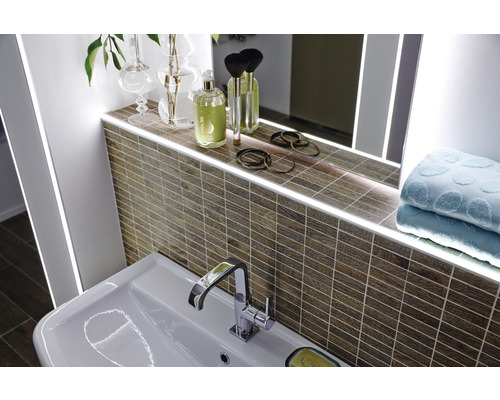 Lavabo de salle de bain avec robinet, miroir avec éclairage et mur carrelé