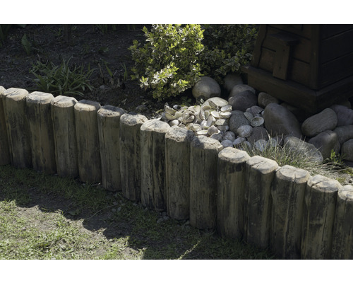 Clôture en bois dans le jardin avec des plantes et des pierres