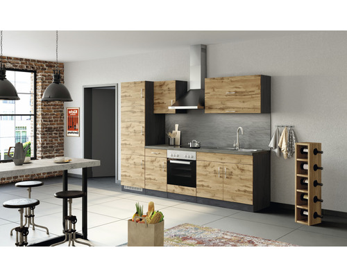 Cuisine équipée avec armoires de cuisine, évier, cuisinière et hotte aspirante dans une pièce lumineuse.