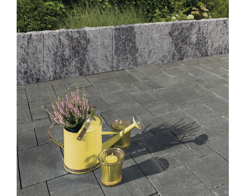 Gartenanlage mit Pflastersteinen, Mauer, Giesskanne und Kerzen