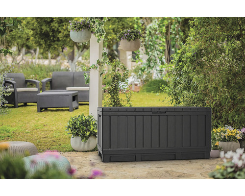Scène de jardin avec un coffre de rangement, un ensemble de salon et des jardinières suspendues.