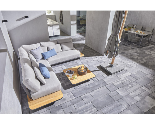 Aussenbereich mit Ecksofa, Tisch, Feuerstelle, Sonnenschirm und Gartentisch mit Stühlen auf Pflastersteinen