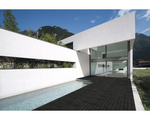 Moderne Architektur eines weißen Hauses mit großer Glasfront, Pool und einer dunklen Fliesenterrasse im Außenbereich.