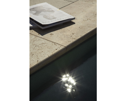 Magazines sur une margelle de piscine à côté d''une piscine