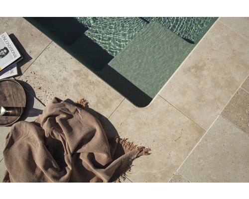 Vue détaillée d''une piscine avec des carreaux en pierre naturelle, un livre, une boisson et un tissu
