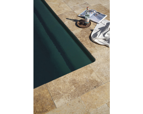 Piscine avec dalles en travertin, bouteille d''eau, magazine, lunettes de soleil et serviette