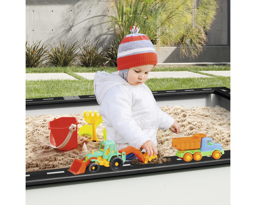 Un jeune enfant joue avec des jouets de bac à sable dans un bac à sable