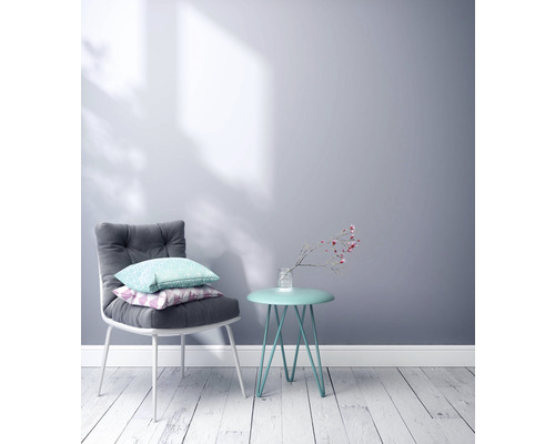 Scène avec une chaise avec des coussins et une table d''appoint avec un vase de fleurs contre un mur