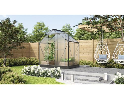 Gewächshaus im Garten mit Pflanzen und Gartendekoration