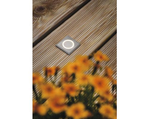 Spot de sol carré encastré avec surface lumineuse ronde sur une terrasse en bois.
