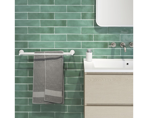 Modernes Badezimmer mit grünen Fliesen, Waschbecken, Handtuchhalter und Handtüchern.