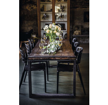 Table de salle à manger avec arrangement floral, verres et chaises noires dans une pièce avec vitrine