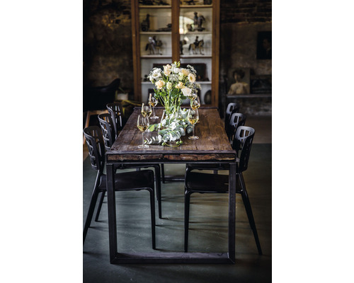 Table de salle à manger avec arrangement floral, verres et chaises noires dans une pièce avec vitrine