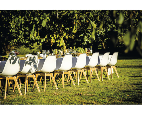 Scène d''une table dressée à l''extérieur avec des chaises blanches sur une pelouse