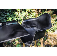 Chaise de jardin noire et table avec couverts à l''extérieur.