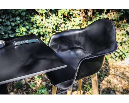 Chaise de jardin noire et table avec couverts à l''extérieur.