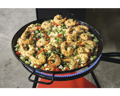Paella Pfanne mit Garnelen und Gemüse auf einem Gasbrenner