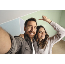 Ein Paar posiert vor einer Wand mit geometrischen Mustern.