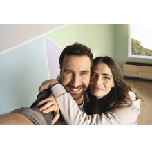 Glückliches Paar in einem frisch renovierten, hellen Raum mit farbigen Akzenten an der Wand