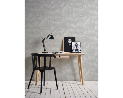 Aménagement avec bureau, chaise, lampe, cadres photo et papier peint à motif de forêt.