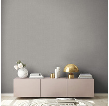 Wohnraum mit grauer Textiltapete, Kommode und dekorativen Elementen