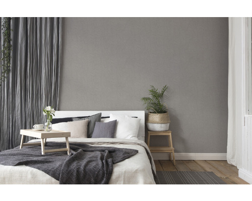 Schlafzimmer mit Bett, Vorhängen und grauer Vliestapete