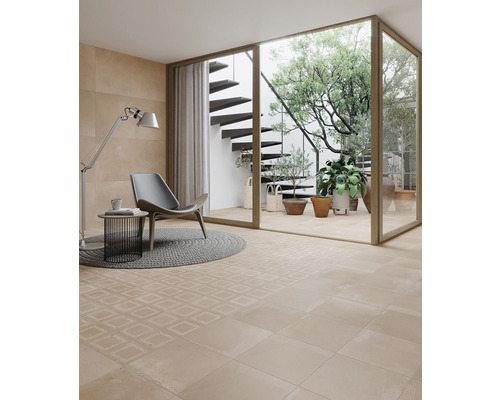 Pièce lumineuse avec carrelage au sol, fauteuil et vue sur un jardin avec escalier