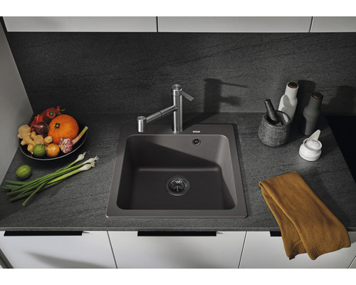 Küchenspüle aus Verbundmaterial mit Wasserhahn auf Küchentheke mit Lebensmitteln