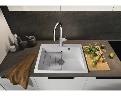 Spüle mit Abtropfgitter, Armatur, Schneidebrett und Lebensmitteln auf einer Küchentheke