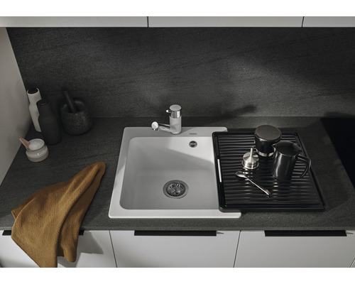 Scène de cuisine avec évier, égouttoir et robinet sur un plan de travail