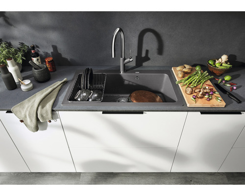 Küchenszene mit Spüle, Armatur, Geschirr, Schneidebrett und Zutaten