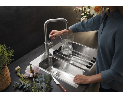 Edelstahlspüle mit Abtropfgestell und Wasserhahn, der ein Glas befüllt