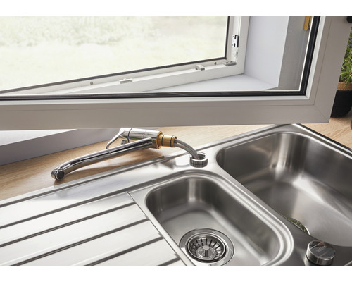 Spüle aus Edelstahl mit Armatur unter einem Fenster