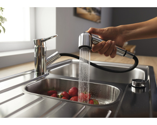 Robinet d''évier avec douchette extractible au-dessus d''un évier rempli de fraises