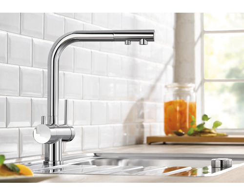 Robinet de cuisine chromé dans l''évier devant un mur de carreaux