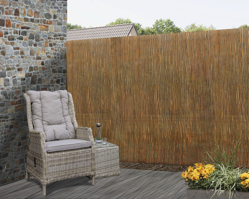 Scène de terrasse avec des meubles en rotin et un paillon de roseaux comme brise-vue