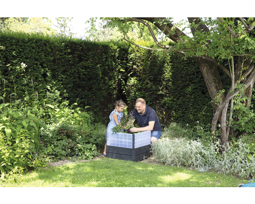 Un père et sa fille travaillent ensemble dans un potager surélevé dans le jardin.