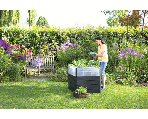 Jardin avec potager surélevé, enfant assis sur un banc et femme travaillant dans le potager surélevé