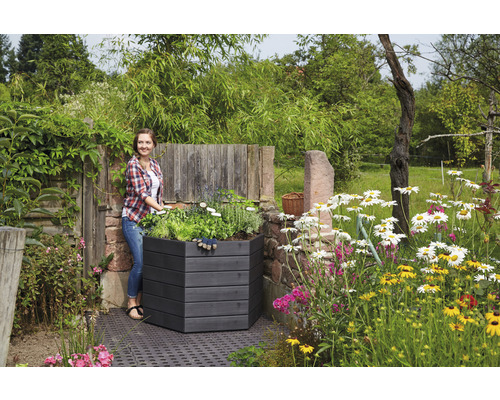 Une femme se tient à côté d''un parterre surélevé en bois dans le jardin.