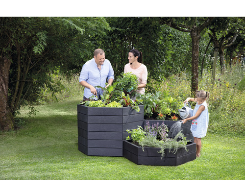 Une famille jardine dans des parterres surélevés dans le jardin.
