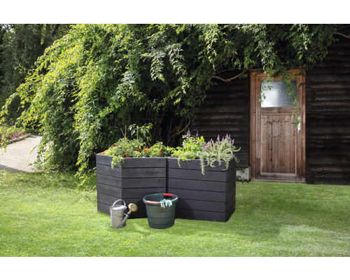 Scène avec deux bacs à fleurs en bois, un seau, un arrosoir et des plantes dans le jardin