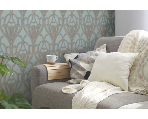 Wohnzimmer mit floral gemusterter Tapete, Couch, Kissen und Decke