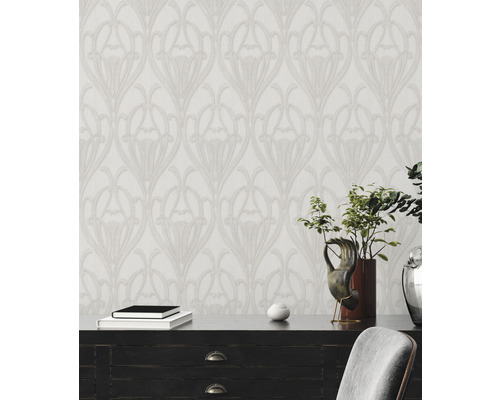 Aménagement avec un papier peint à motifs de style Art nouveau floral derrière une commode.