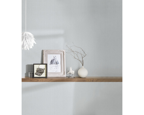 Pièce lumineuse avec papier peint textile, décorée de cadres photo, d''un vase et d''une étagère